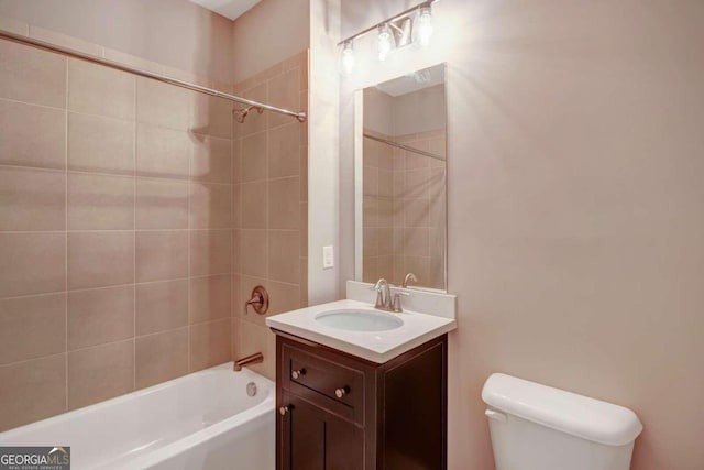 full bathroom with tiled shower / bath, vanity, and toilet