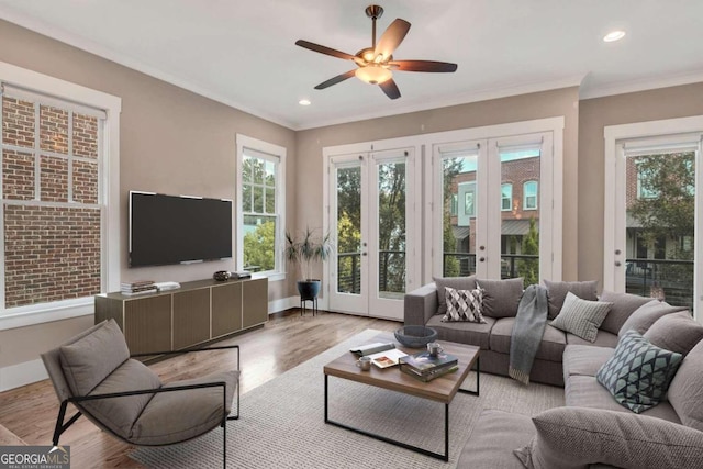 living room featuring light wood-type flooring, crown molding, ceiling fan, and french doors