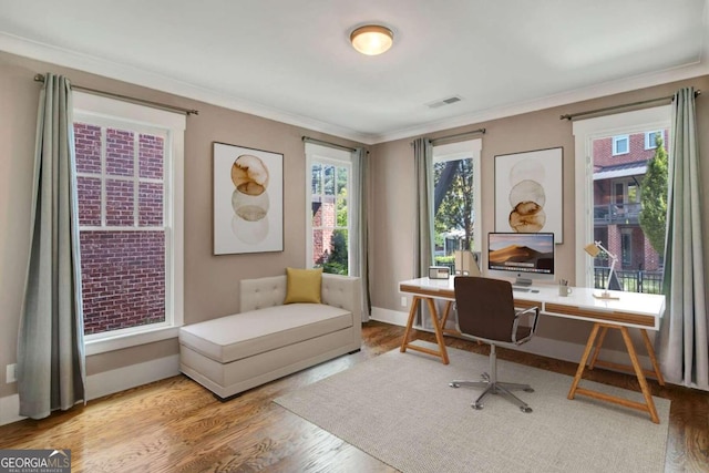 office with light hardwood / wood-style flooring and crown molding