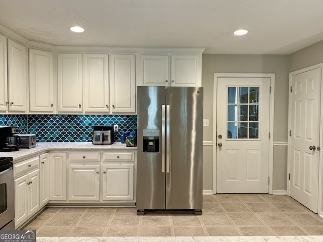 kitchen featuring white cabinetry, decorative backsplash, stainless steel fridge, and light stone countertops