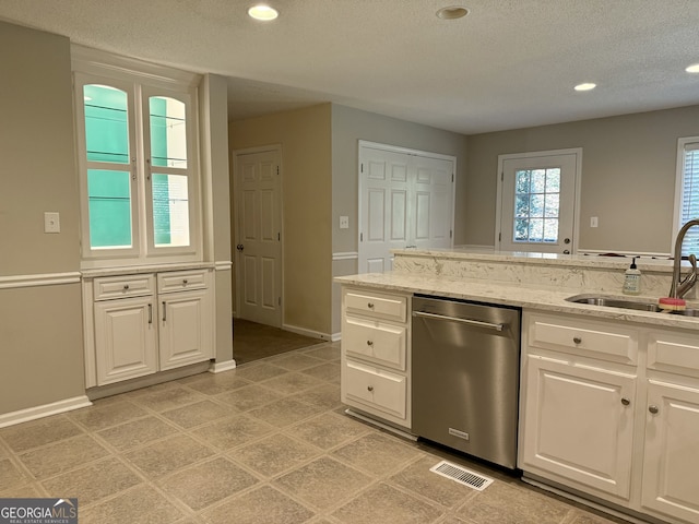 kitchen with white cabinets, stainless steel dishwasher, sink, and light stone counters