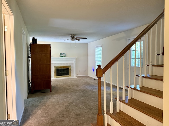 interior space featuring carpet flooring, a tile fireplace, and ceiling fan