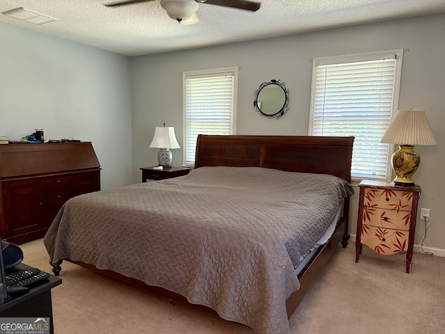 carpeted bedroom featuring ceiling fan, a textured ceiling, and multiple windows