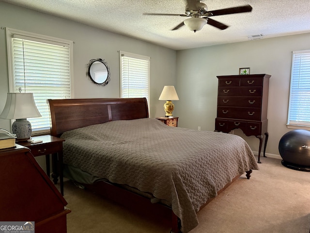 carpeted bedroom featuring multiple windows, a textured ceiling, and ceiling fan