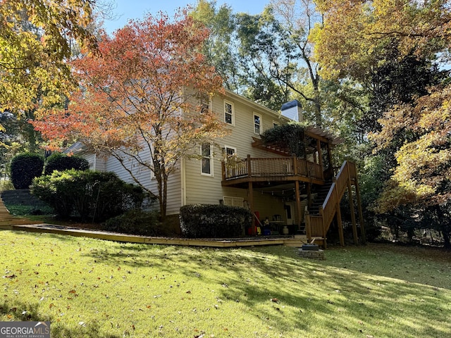 rear view of house featuring a wooden deck and a lawn