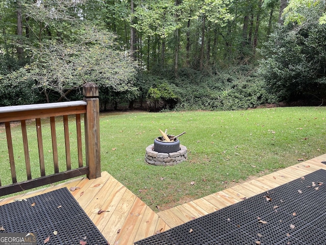 wooden terrace with a yard and an outdoor fire pit