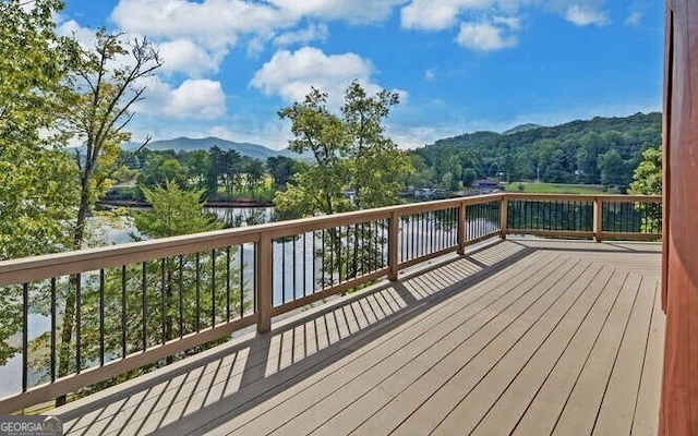 wooden deck with a water and mountain view