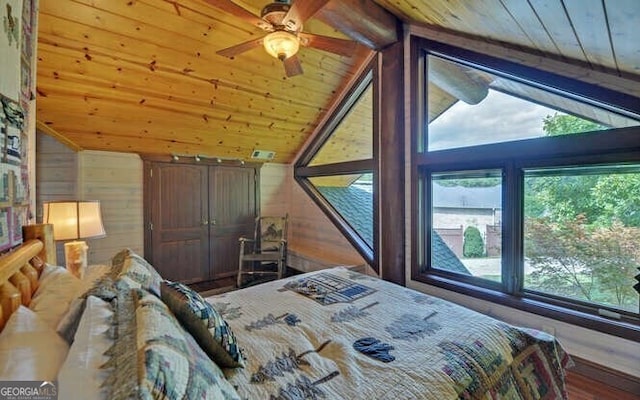 bedroom featuring lofted ceiling with beams, wooden walls, ceiling fan, and wood ceiling