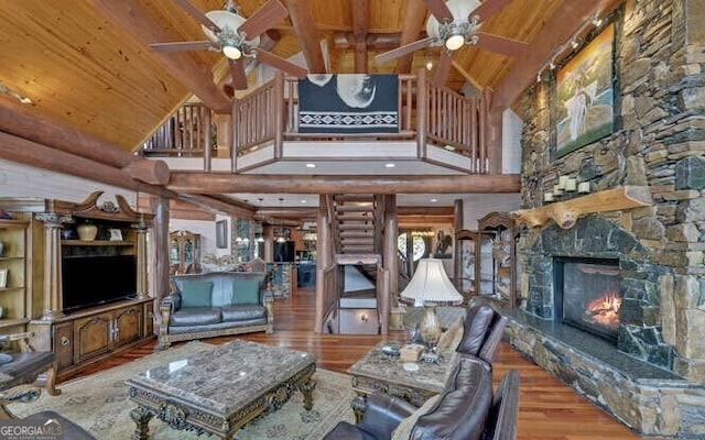 living room with a stone fireplace, hardwood / wood-style floors, high vaulted ceiling, and wood ceiling