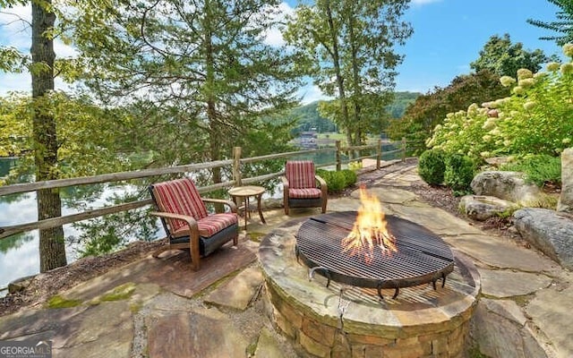 view of patio with a fire pit and a water view