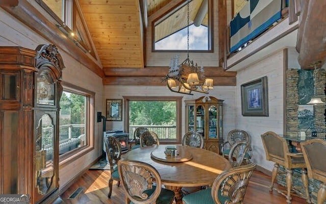 dining area featuring wooden walls, wood-type flooring, and high vaulted ceiling