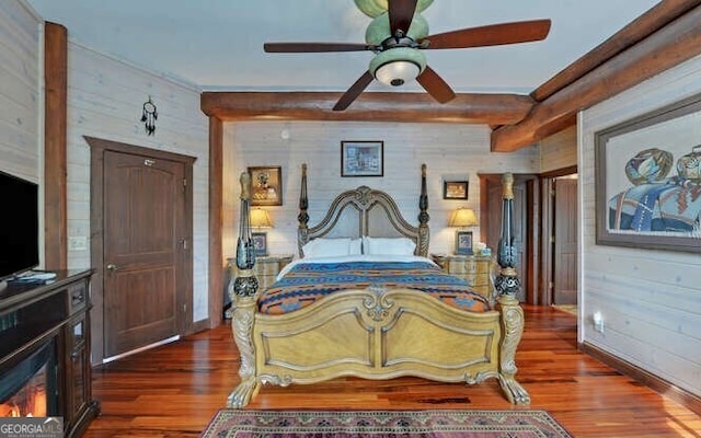 bedroom featuring ceiling fan, wood walls, and dark hardwood / wood-style floors