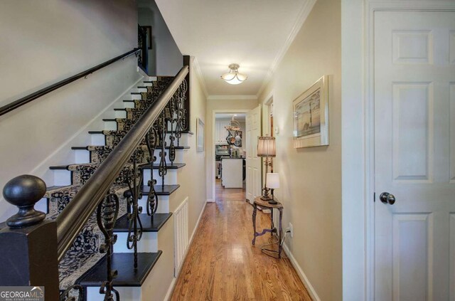 corridor with crown molding and light hardwood / wood-style floors