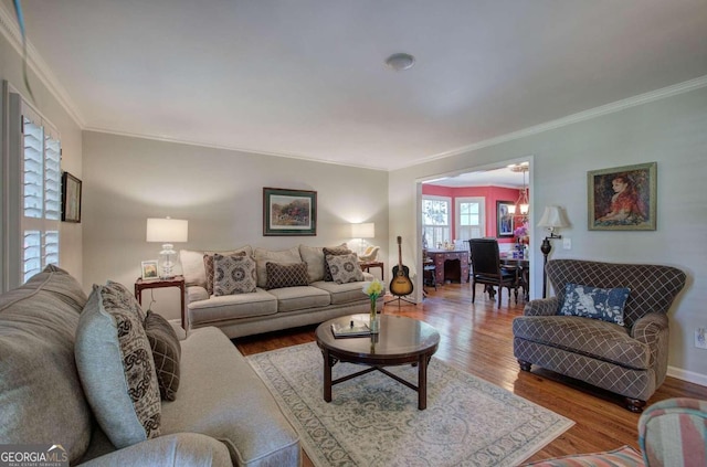 living room with wood-type flooring, an inviting chandelier, and crown molding