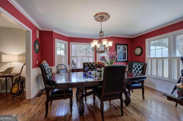 dining area with crown molding, wood-type flooring, and a notable chandelier