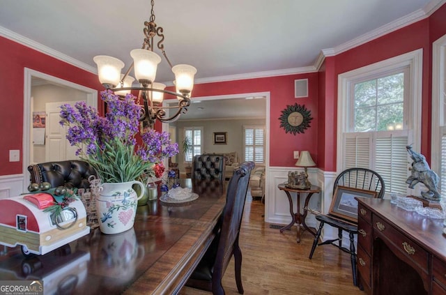 dining area featuring ornamental molding, a notable chandelier, and light wood-type flooring