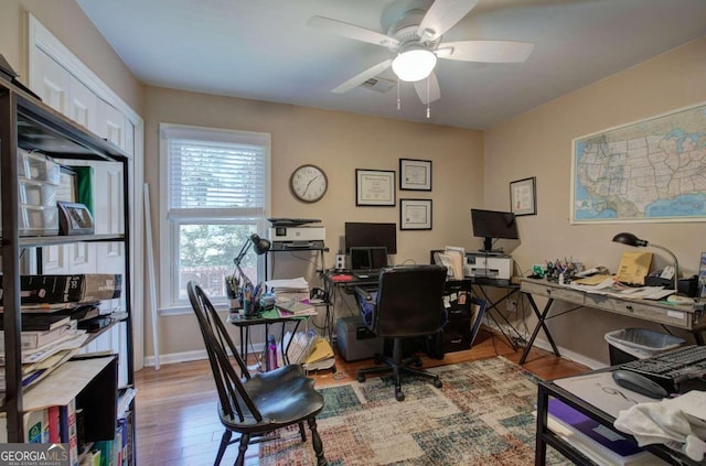 home office with light wood-type flooring and ceiling fan