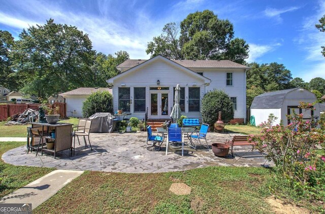 rear view of house with a yard, a shed, a fire pit, and a patio area