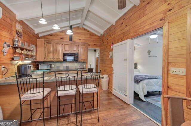 kitchen featuring light wood-type flooring, backsplash, kitchen peninsula, lofted ceiling with beams, and a breakfast bar area