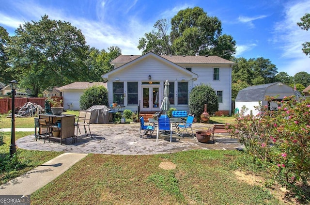 back of property with an outbuilding, a lawn, and a patio area