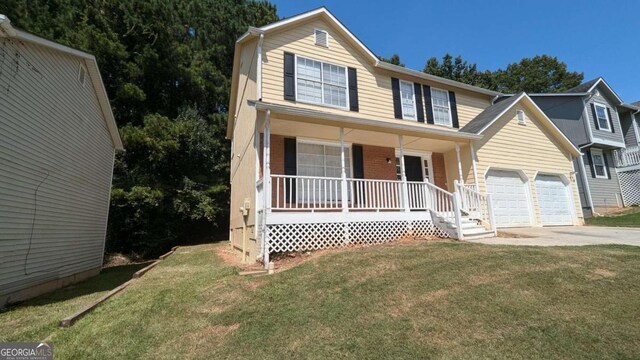 view of front of home featuring a porch, a garage, and a front yard