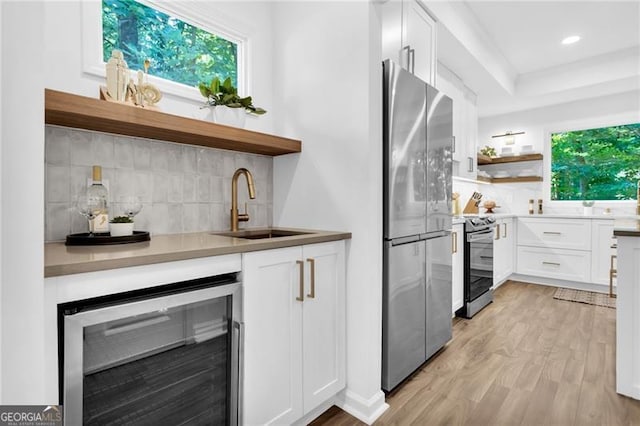 kitchen with plenty of natural light, beverage cooler, sink, and appliances with stainless steel finishes