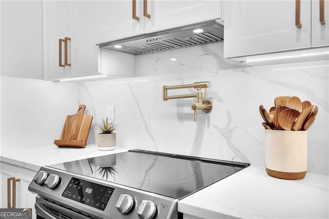 details featuring light stone counters, stainless steel electric stove, white cabinetry, and extractor fan