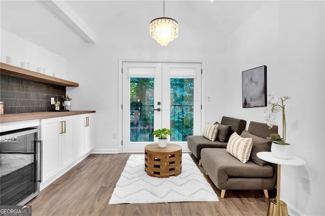 living room with beverage cooler, lofted ceiling, a chandelier, and light hardwood / wood-style flooring