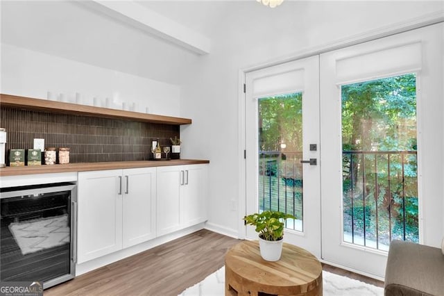 bar featuring wooden counters, white cabinetry, beverage cooler, and light hardwood / wood-style flooring