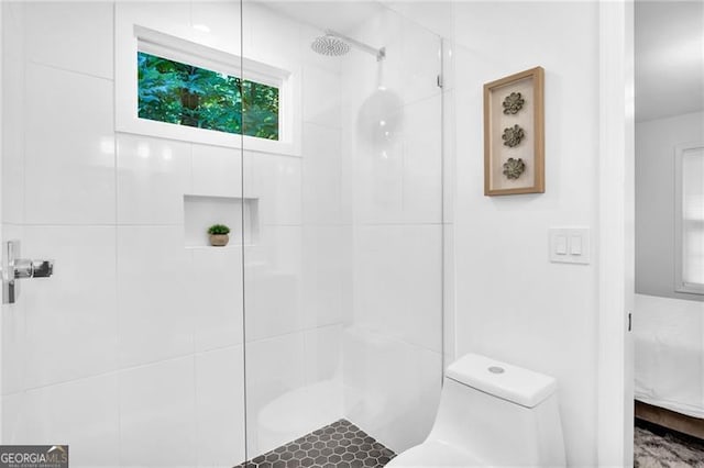 bathroom featuring toilet and a tile shower