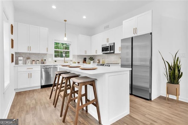 kitchen featuring a center island, stainless steel appliances, white cabinetry, and light hardwood / wood-style flooring