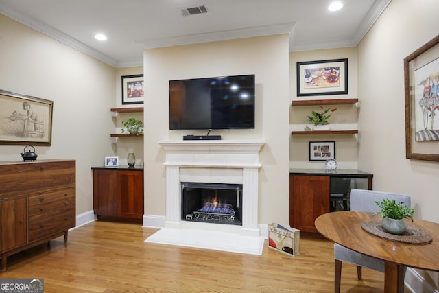 living room with light wood-type flooring and ornamental molding