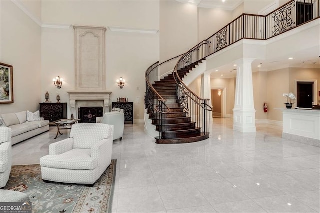 living room featuring a high ceiling, ornamental molding, and ornate columns