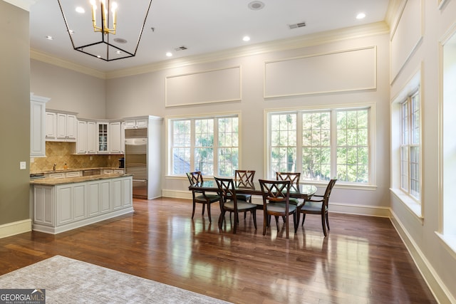 dining space with ornamental molding, a high ceiling, a notable chandelier, and dark hardwood / wood-style flooring