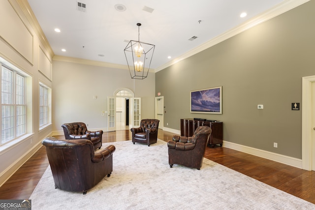 living area featuring crown molding, wood-type flooring, and a chandelier