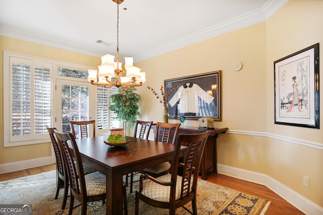 dining area featuring crown molding, light hardwood / wood-style flooring, and a notable chandelier