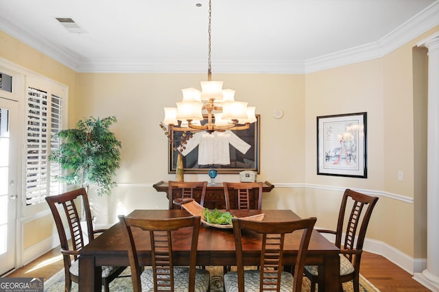 dining space with hardwood / wood-style flooring, crown molding, and a notable chandelier