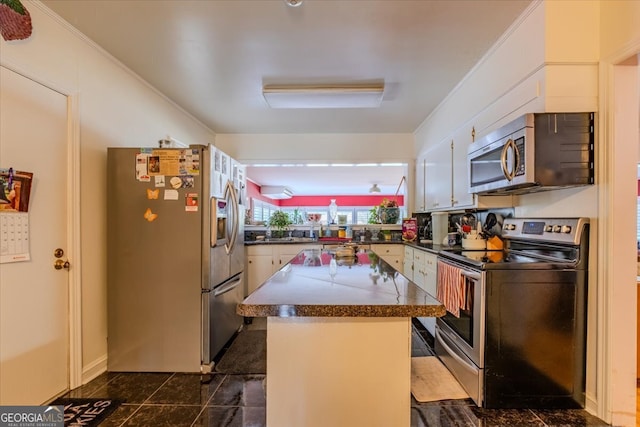 kitchen featuring dark tile patterned flooring, white cabinets, stainless steel appliances, and ornamental molding