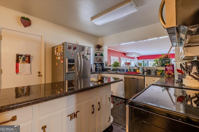 kitchen with dark stone counters, appliances with stainless steel finishes, and white cabinets