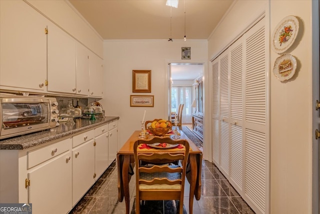 kitchen with white cabinets, dark tile patterned floors, and crown molding