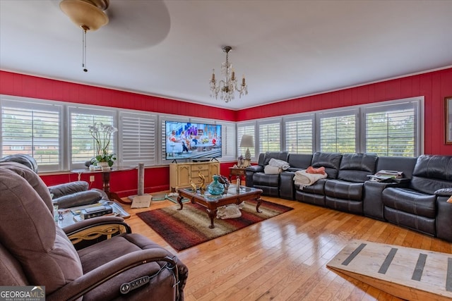 living room featuring light wood-type flooring, ceiling fan with notable chandelier, and a healthy amount of sunlight