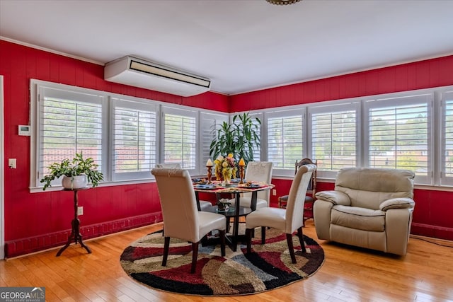 dining area featuring a wall mounted AC, a wealth of natural light, and light hardwood / wood-style flooring