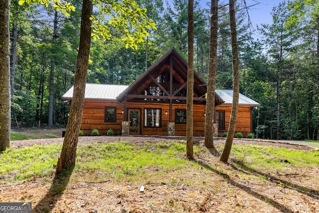 view of front of house with covered porch, metal roof, and a view of trees