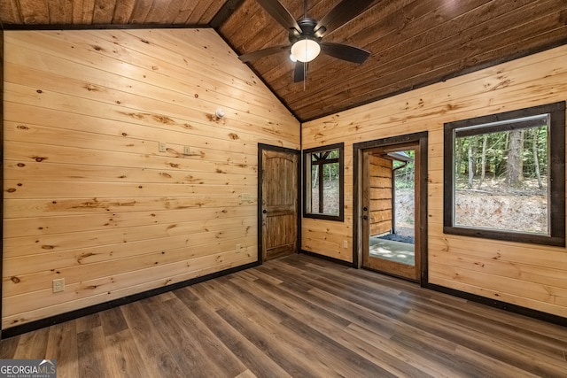 unfurnished room featuring wood walls, wooden ceiling, dark wood-type flooring, lofted ceiling, and ceiling fan