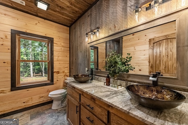 bathroom with vanity, toilet, wooden walls, and wood ceiling