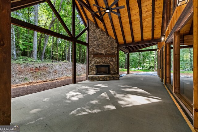 unfurnished sunroom with an outdoor stone fireplace, wood ceiling, lofted ceiling with beams, and ceiling fan