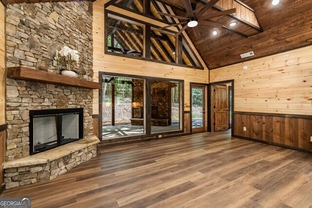 unfurnished living room featuring a fireplace, wood walls, ceiling fan, wooden ceiling, and hardwood / wood-style flooring