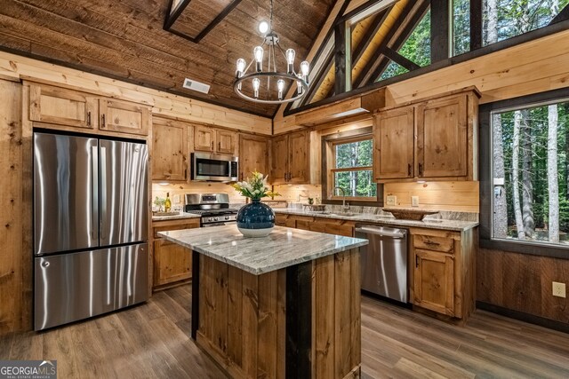 kitchen with a center island, a notable chandelier, light stone countertops, and appliances with stainless steel finishes