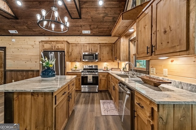 kitchen with appliances with stainless steel finishes, light stone countertops, sink, and a notable chandelier