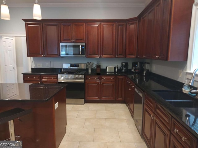 kitchen with dark stone counters, ornamental molding, stainless steel appliances, sink, and pendant lighting